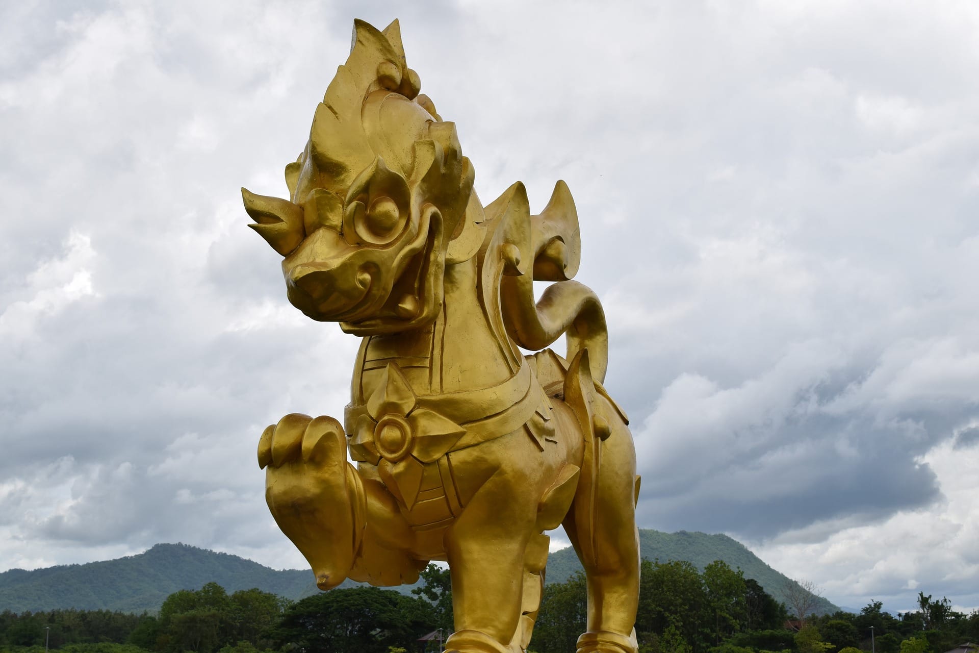 The giant golden Singha lion statue at Singha Park, Chiang Rai, with mountains behind