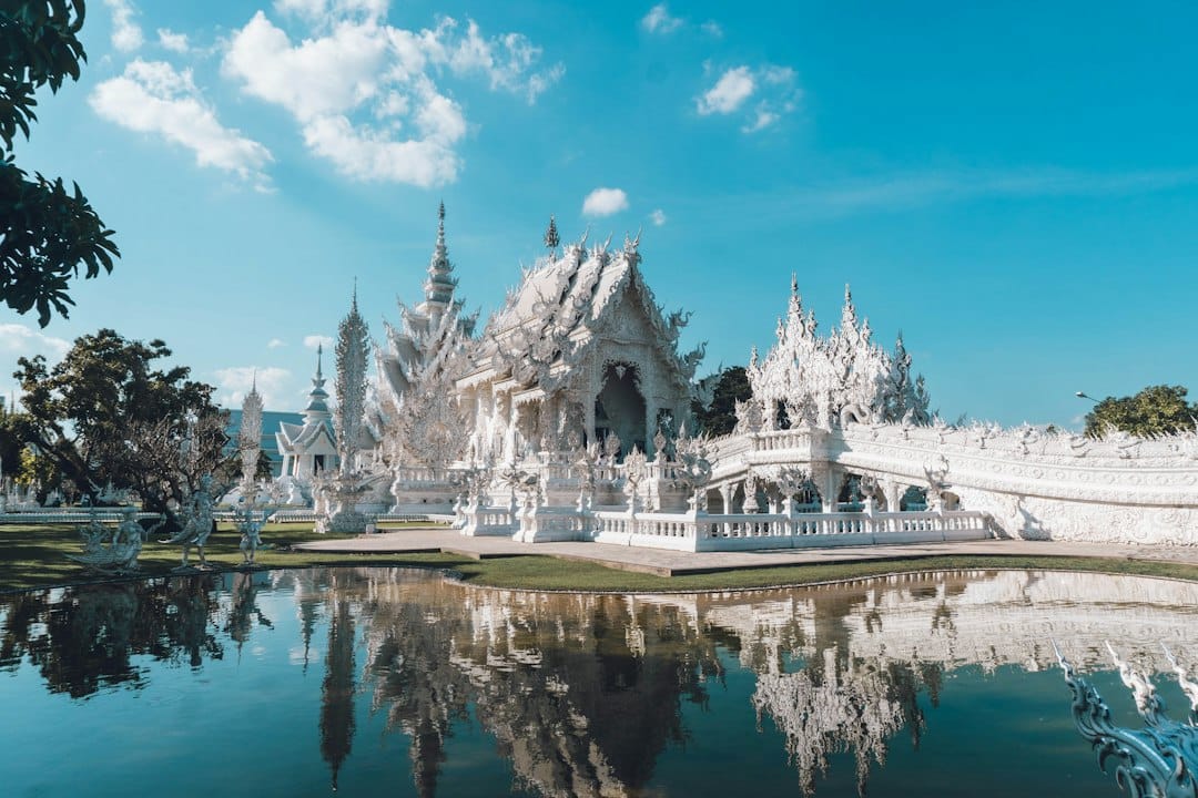 The all-white Wat Rong Khun (White Temple) reflected in its pond, Chiang Rai