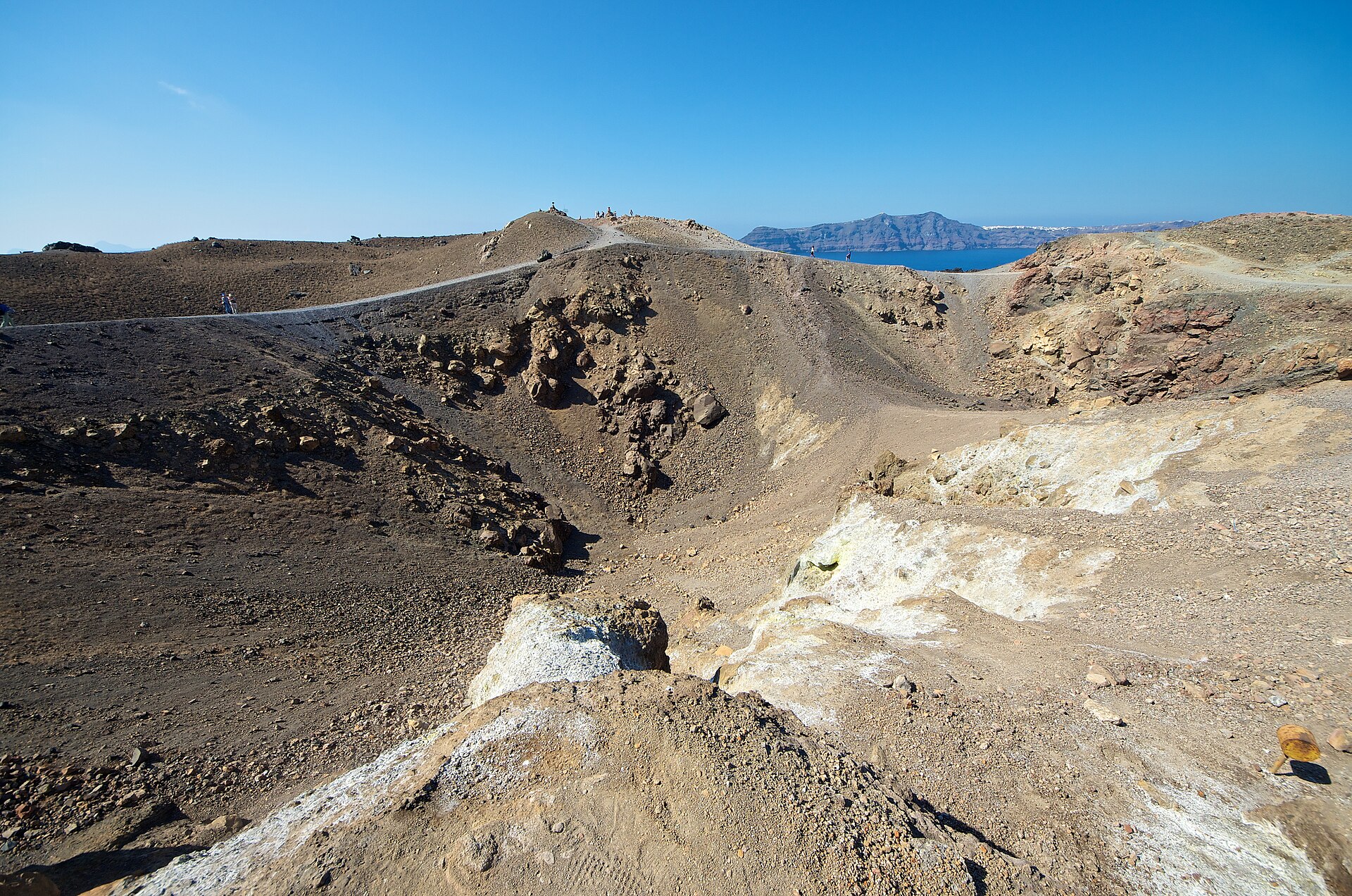 Volcanic crater and trail on Nea Kameni island with the Santorini caldera rim behind