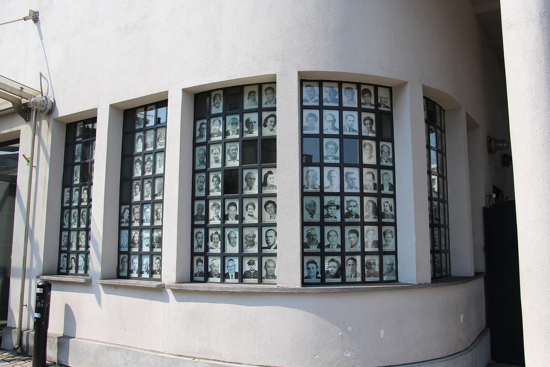 Windows of the Oskar Schindler Enamel Factory museum filled with black-and-white portrait photographs of Holocaust survivors