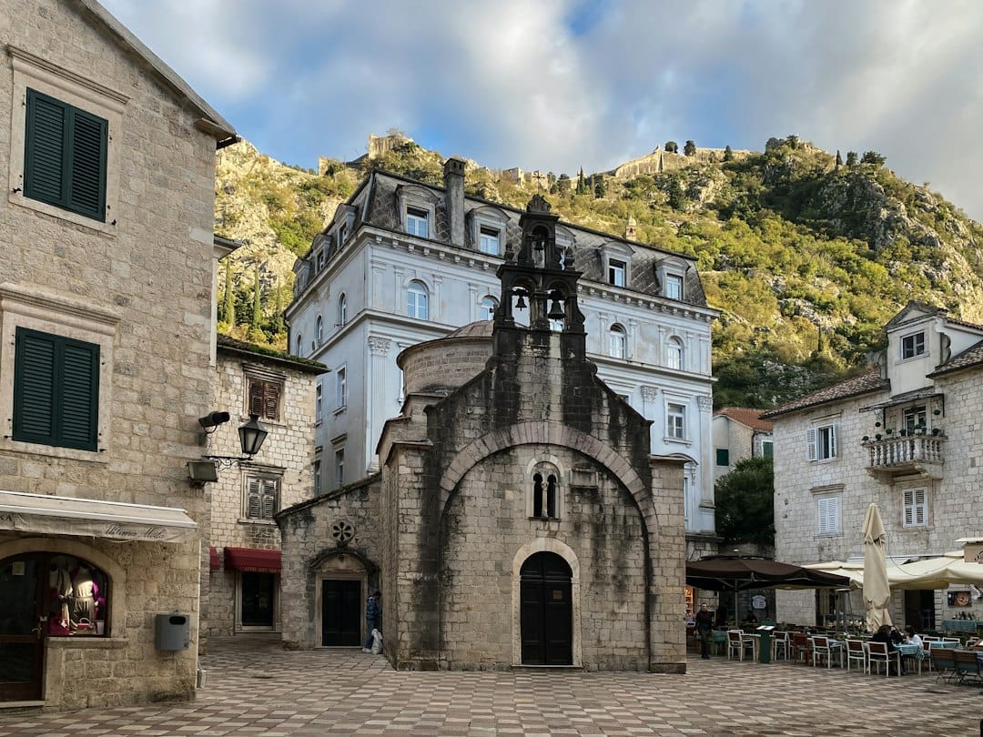 A small Romanesque stone church on a square in Kotor Old Town with the fortress hill rising behind
